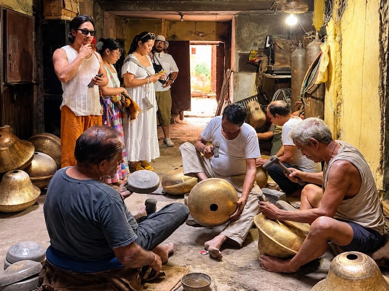 Travellers watching traditional metal artisans at work in Rajasthan