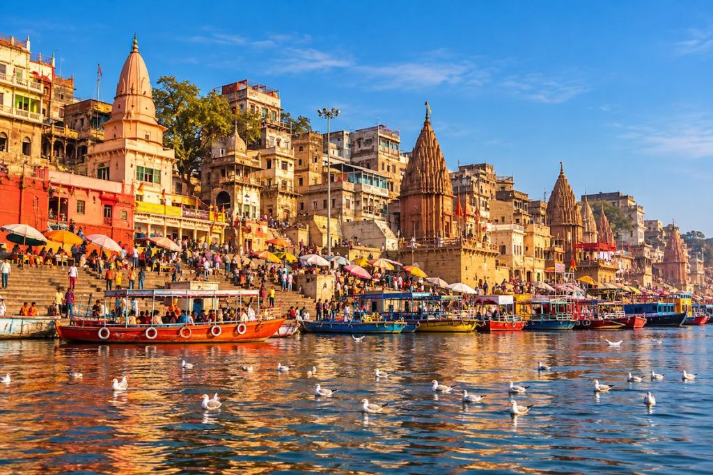Dashashwamedh Ghat in Varanasi with historic temples, colourful boats and pilgrims along the River Ganges.