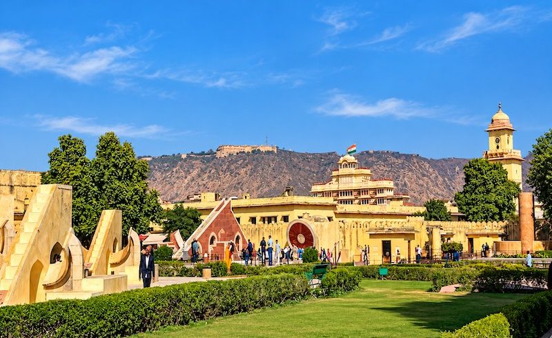 Historic Jantar Mantar astronomical observatory in Jaipur, Rajasthan, with traditional instruments and Nahargarh Fort in the background.